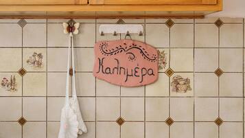 A kitchen with a tiled backsplash, a hanging white cloth, and a pink sign with the name "Kandhypega".