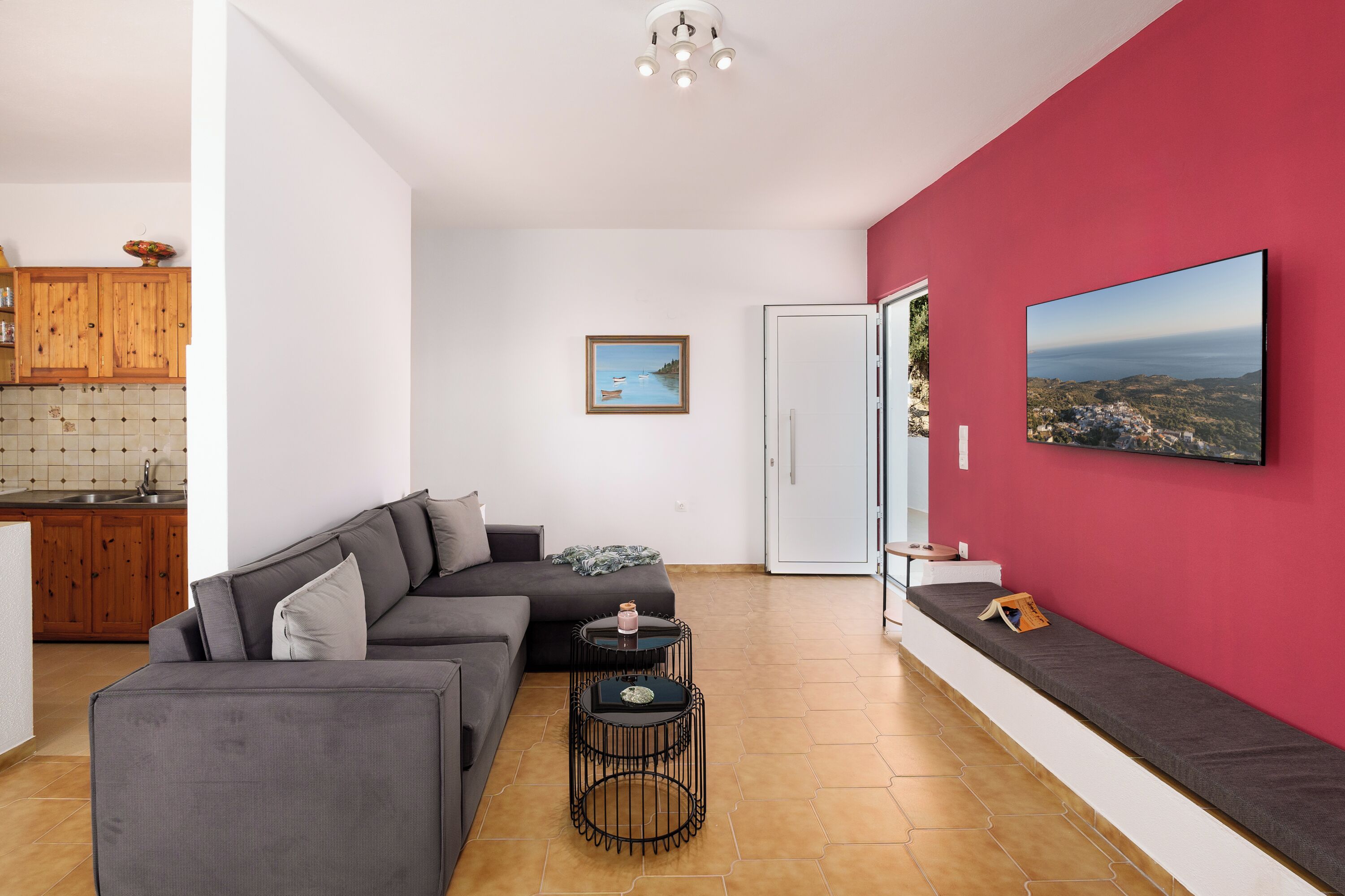 Una sala moderna con un sofá gris, una mesita redonda y una pared de acento roja.