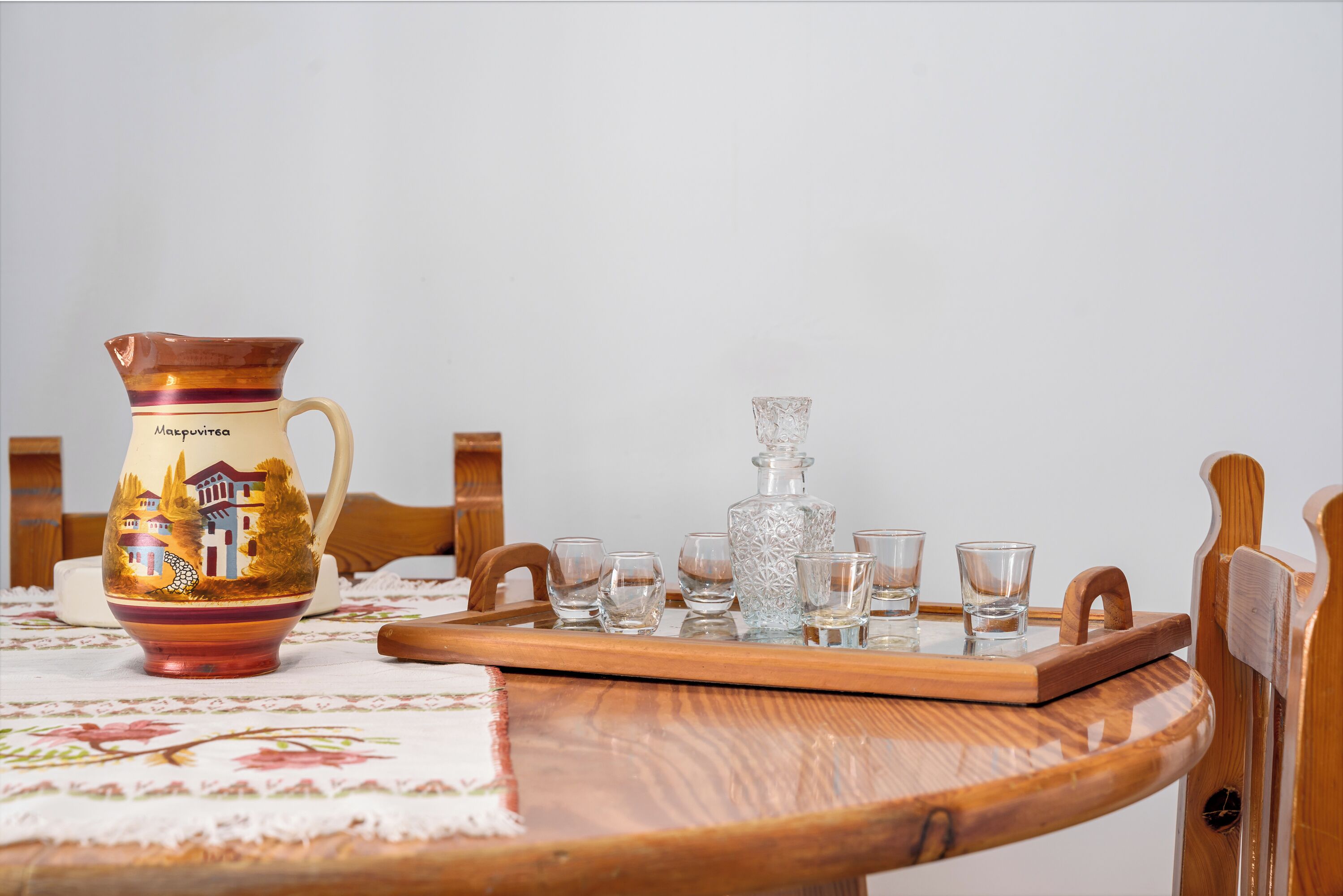 A wooden table with a tray holding a pitcher, a decanter, and several shot glasses.