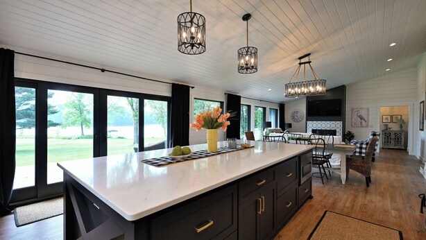 A modern kitchen with a large island, dark cabinetry, and pendant lighting.