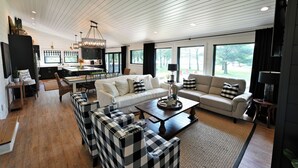 A spacious living area with a large sofa, a coffee table, and a dining area with a chandelier.