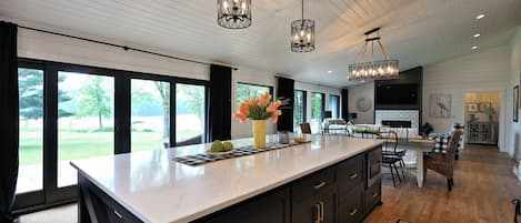 Una cocina moderna con una isla grande, armarios oscuros e iluminación colgante.