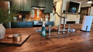 Une cuisine avec des meubles de couleur vert foncé, une cuisinière en acier inoxydable et un plan de travail en bois.