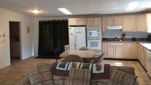 A compact living space with a kitchenette, a dining area, and a sofa with patterned cushions. - 3 bedroom, 3 bath home in Matewan, WV. 1 mile from the Devil Anse trailhead. (Matewan)