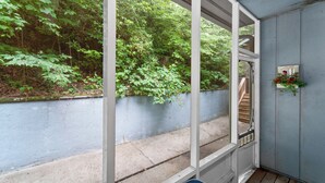 Ein Zimmer mit Blick auf einen üppigen grünen Wald durch große Fenster, einer Holztreppe und einer blauen Wand mit einem Willkommensschild.