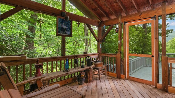 Eine Holzterrasse mit Bänken und Tischen, umgeben von üppigem Grün.