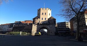 A historic stone gate with a tower, surrounded by modern buildings.