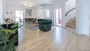 A spacious living area with a dining table, a green sofa, and a staircase leading to an upper floor. - Casa da Torre in Portimão (Portimão)