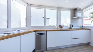 A modern kitchen with a dishwasher, wooden countertop, white cabinets, and large windows. - Casa da Torre in Portimão (Portimão)