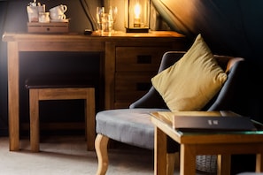 A cozy room with a wooden desk, a cushioned chair, a small table, and a lamp. - Corner House (Canterbury)