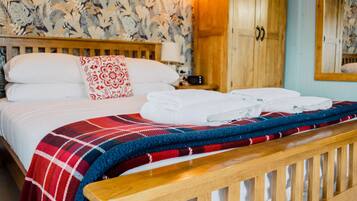 A neatly made bed with a plaid blanket, a wooden headboard, and a nightstand with a lamp.