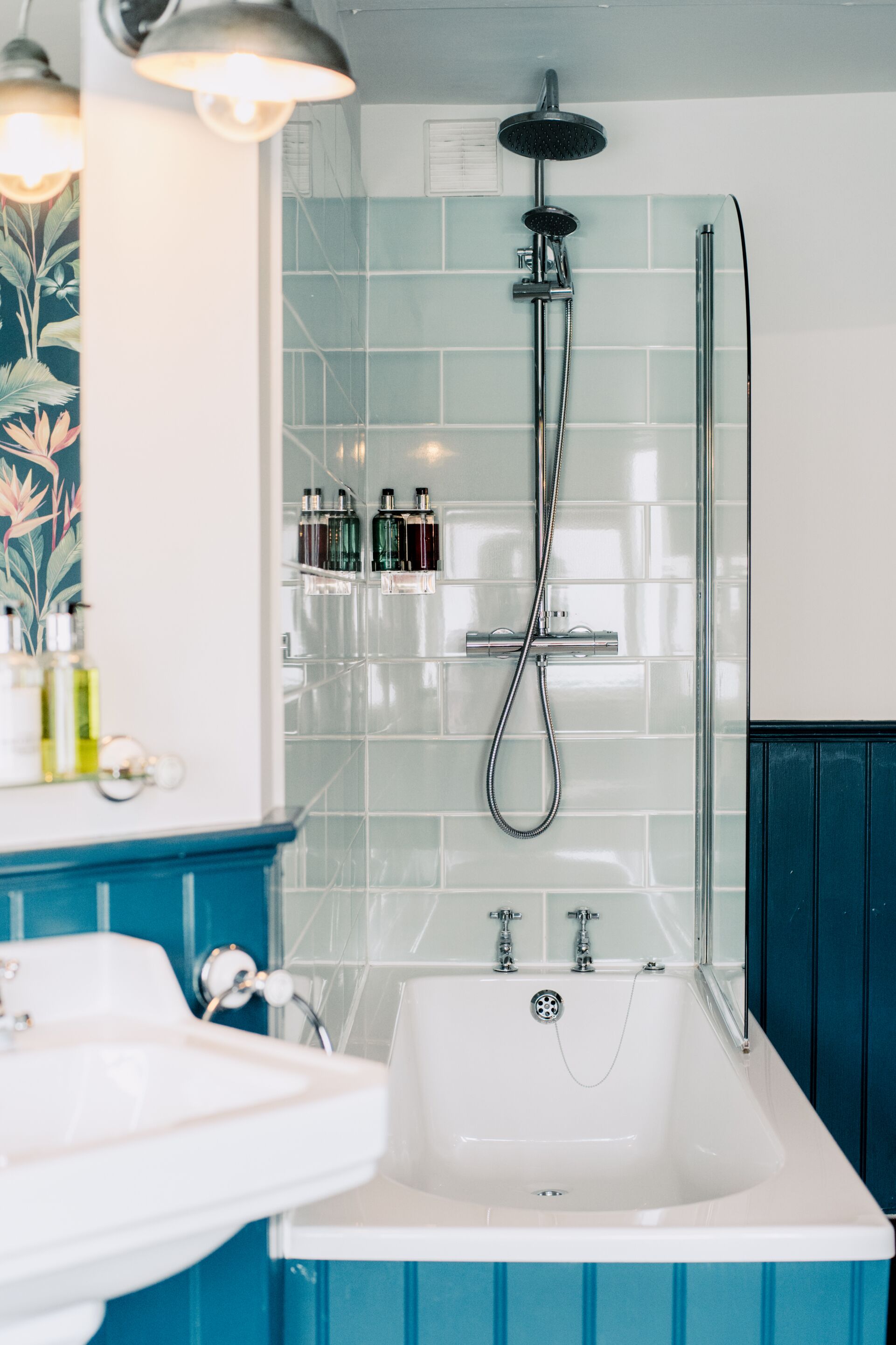 A bathroom with a white bathtub, a showerhead, and a sink.