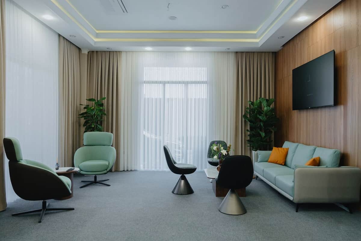 A modern living room with a sofa, two armchairs, a coffee table, and a TV mounted on the wall.