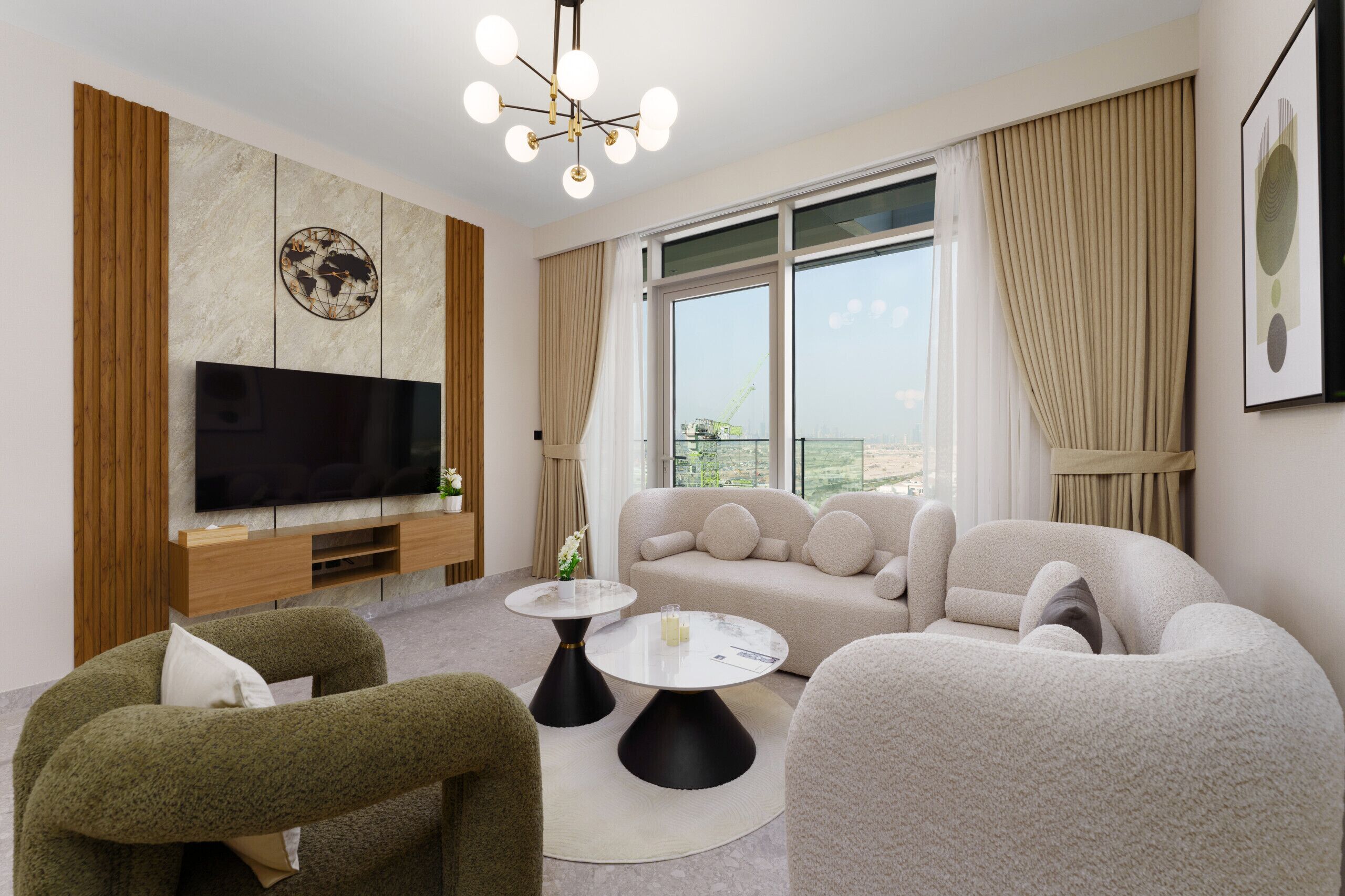 A modern living room with a flat-screen TV, a beige sofa, two armchairs, and a round coffee table.