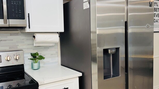 A modern kitchen with white cabinets, stainless steel appliances, and a built-in water dispenser.