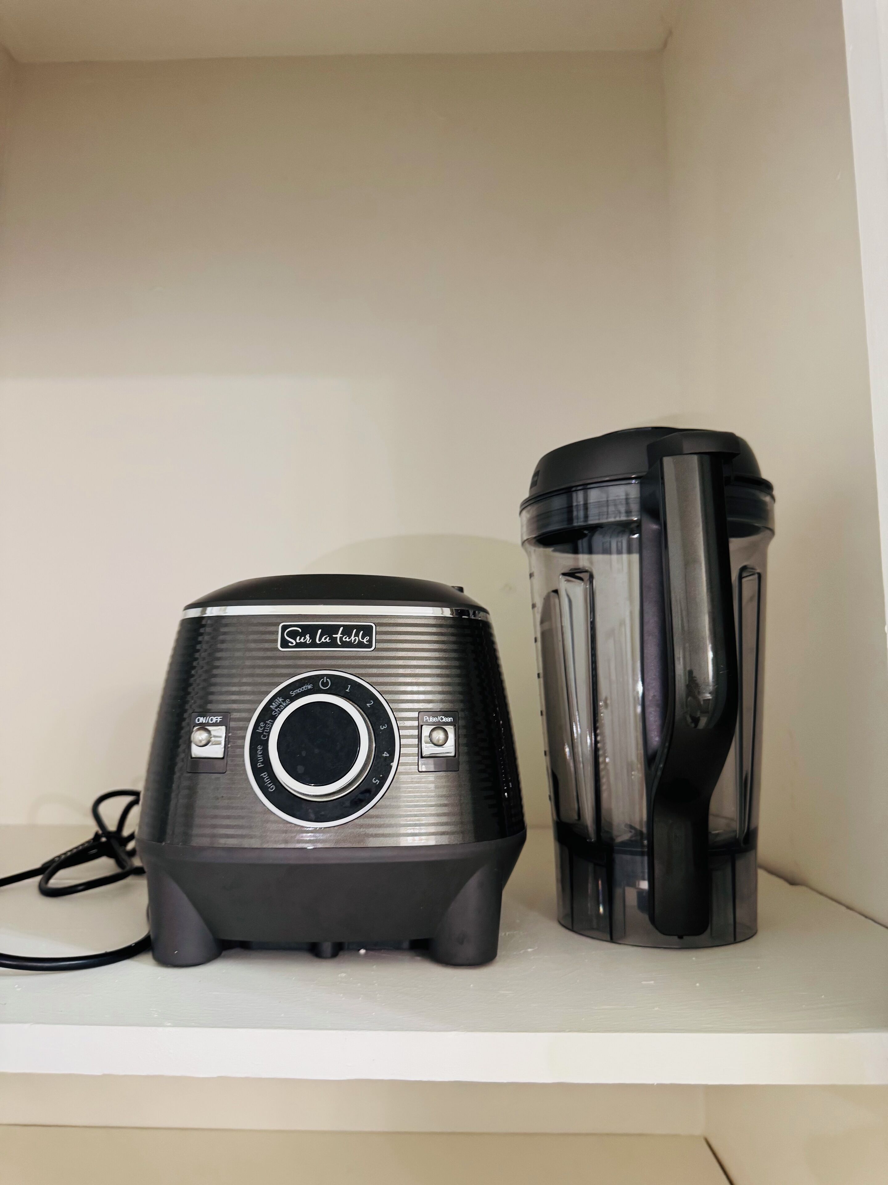 Uma cozinha com um liquidificador e um recipiente na bancada.