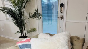 A beige sofa with a fluffy white pillow and a striped blanket.