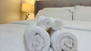 A neatly made bed with rolled white towels, a bedside lamp, and two framed pictures of the moon on the wall.
