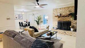 A living room with a gray sofa, a coffee table, and a brick wall.