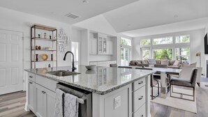 Una cocina moderna con armarios blancos, encimera de granito y una isla integrada con fregadero.