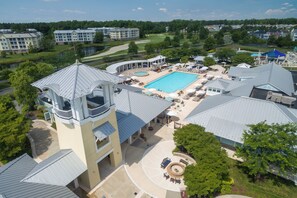 A hotel with a swimming pool, outdoor seating, and a golf course in the background. - Golf, Pools, Tennis and more! 23704 Brickwalk Drive (Millsboro)