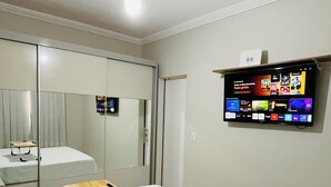 Une chambre d’hôtel équipée d’un lit, d’un bureau, d’un ventilateur de plafond, d’un téléviseur fixé au mur et d’un miroir.
