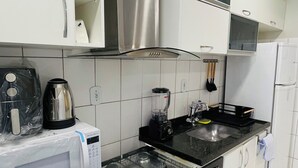 Une cuisine avec des meubles blancs, une cuisinière, un four à micro-ondes et un réfrigérateur.