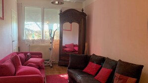 A living room with a red sofa, a brown leather sofa, a wooden cabinet, and a radiator.