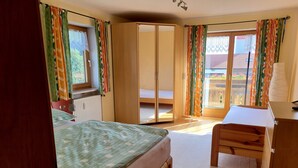 Un dormitorio con cama, escritorio, armario y vistas al exterior.
