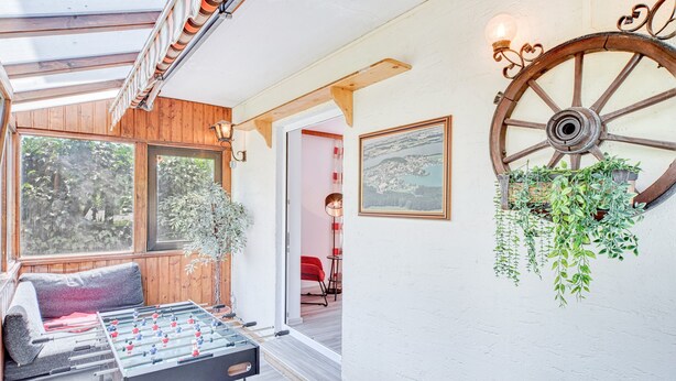 A cozy room with a foosball table, wooden beams, a large wheel wall decoration, and a hanging plant. - Apartment 'Seenähe' with Shared Terrace, Shared Garden and Wi-Fi (Mattsee)