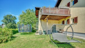 A residential building with a balcony, a trampoline, and a hammock in the yard. - Apartment 'Seenähe' with Shared Terrace, Shared Garden and Wi-Fi (Mattsee)
