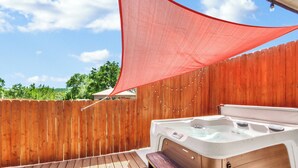 Ein Whirlpool mit einer Holzterrasse und einem Holzzaun im Hintergrund.