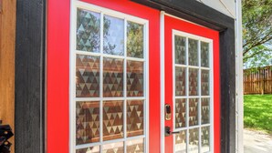 Eine rote Tür mit geometrisch gemusterten Glasfenstern und einem schwarzen Rahmen.