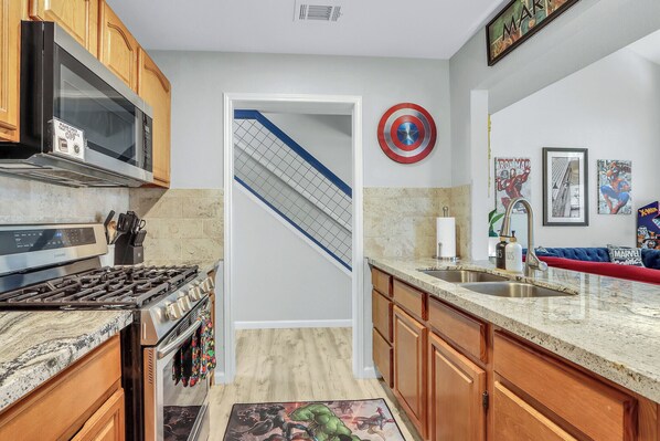 A kitchen with wooden cabinets, a stainless steel stove, a microwave, and a sink.