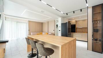 Eine moderne Küche mit einer zentralen Kochinsel, Barhocker und einem Essbereich mit einer Couch.