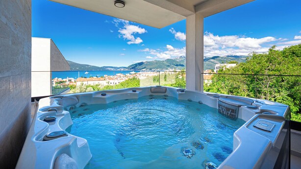 Un bain à remous offrant une vue panoramique sur une ville côtière et les montagnes.