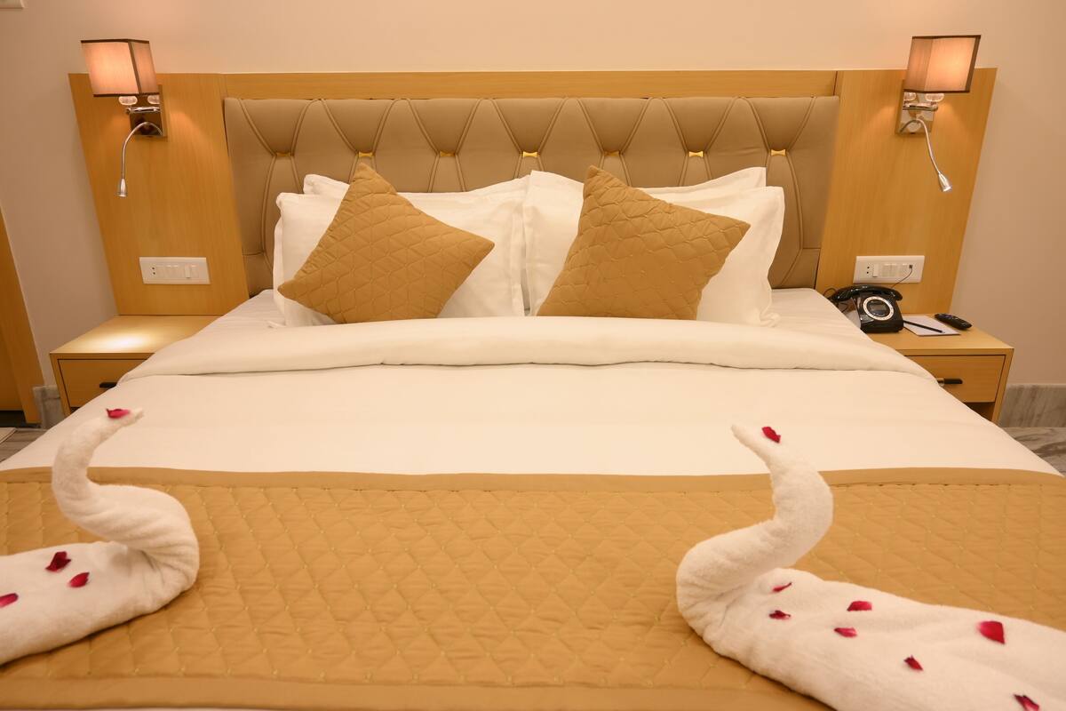 A hotel room with a large bed, two bedside lamps, a nightstand, and a telephone.