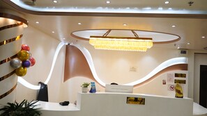 A reception desk with a modern design, a chandelier, and a wall with balloons. - Hotel Kashi Crown (Varanasi)