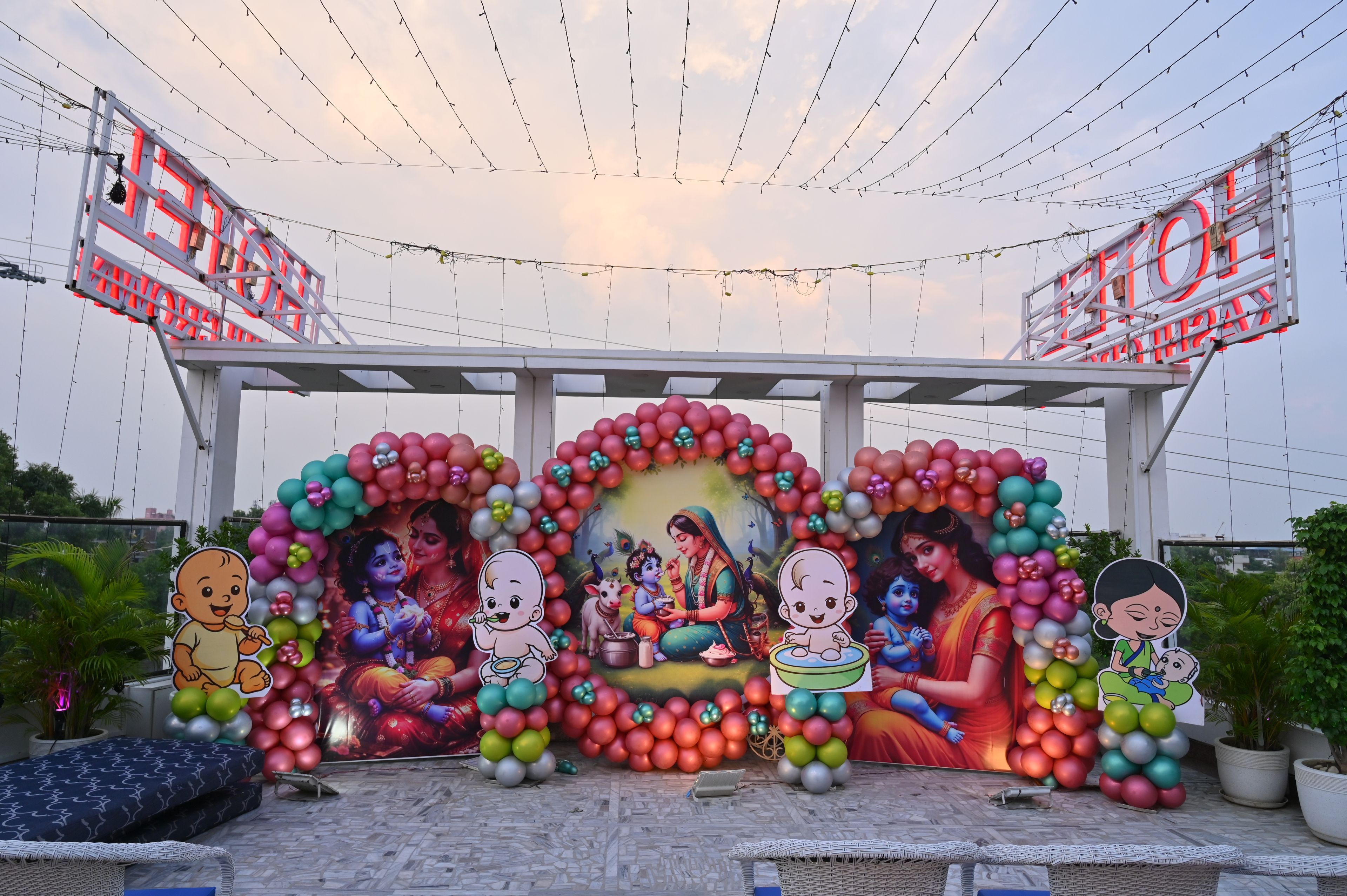 Un espacio exterior decorado con un escenario, globos y un letrero.