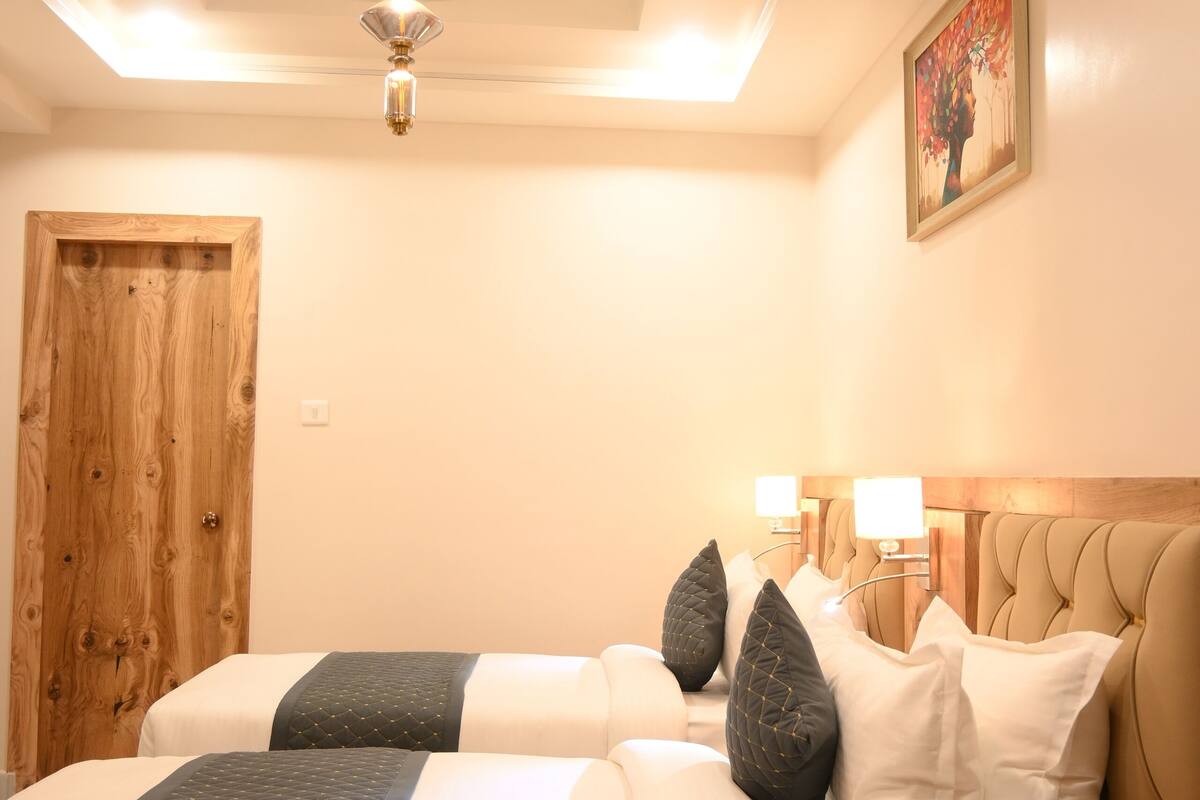 A bedroom with a wooden door, a bed with white and dark bedding, and three ceiling fans.