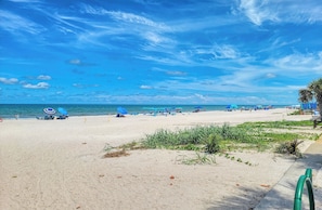Una playa con cielos despejados, una orilla arenosa y algunas sombrillas.