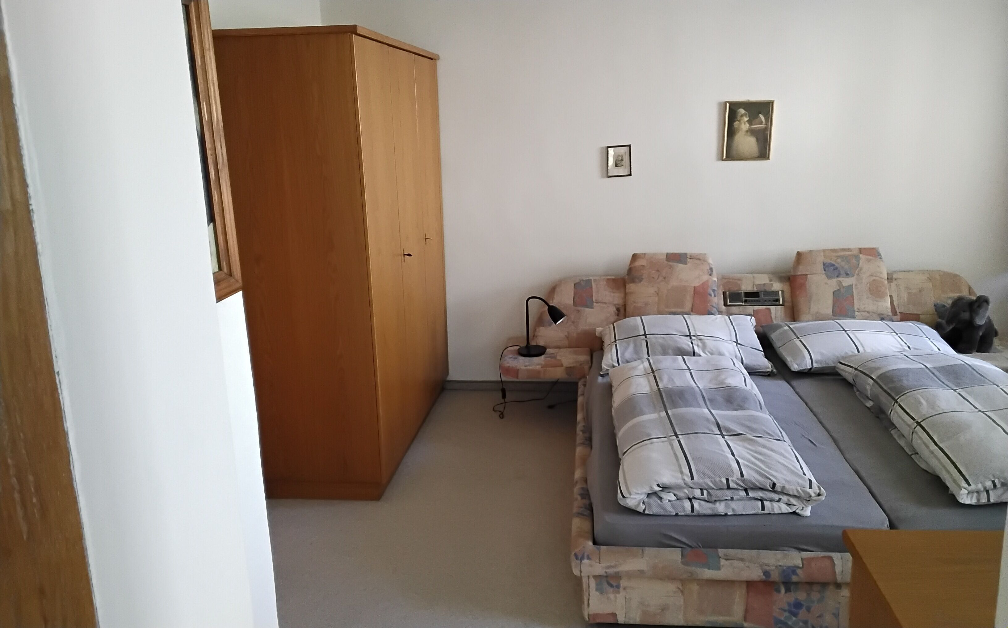 Un dormitorio con cama, una silla, un armario y una mesita.