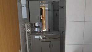 Una cucina moderna con mobili bianchi, un lavello in acciaio inox e una lavatrice integrata.