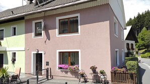 Un edificio su due piani con un balcone, un cancello e piante in vaso.