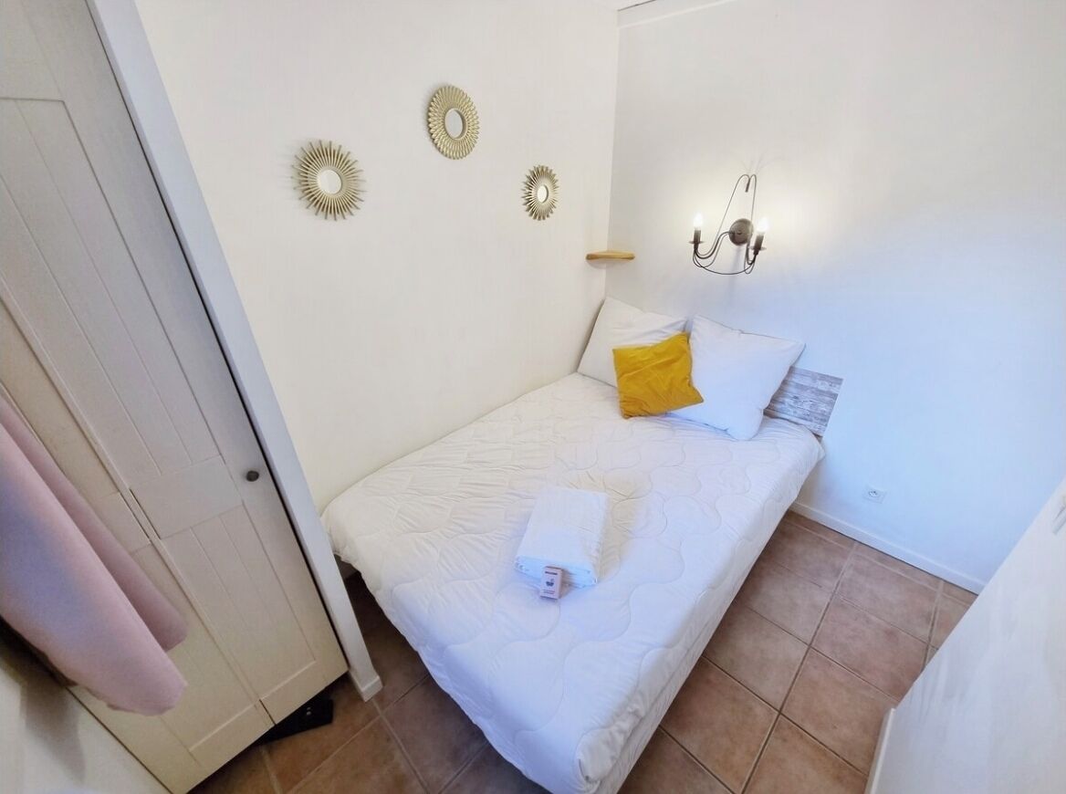 Un dormitorio con una cama, un aplique de pared y una puerta.