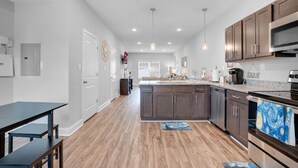 A modern kitchen with wooden flooring, dark cabinets, and stainless steel appliances.