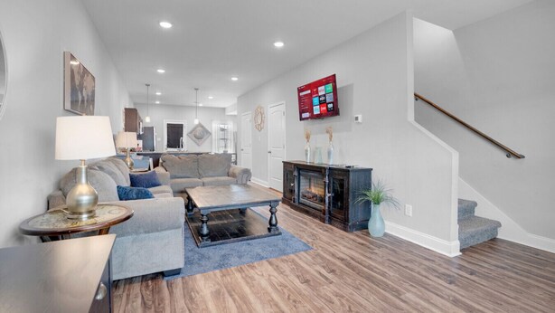 A modern living room with a fireplace, a staircase, and a mounted TV.