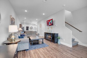 Ein modernes Wohnzimmer mit Kamin, Treppe und Wandfernseher.