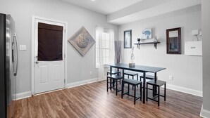 A modern kitchen with a refrigerator, a dining table with chairs, and decorative wall art.