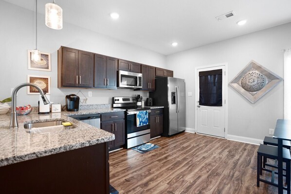 A modern kitchen with dark wood cabinets, stainless steel appliances, and a granite countertop. - Timeless Escape – Modern Comfort Near Nashville Free Wi-Fi and Parking (Clarksville)